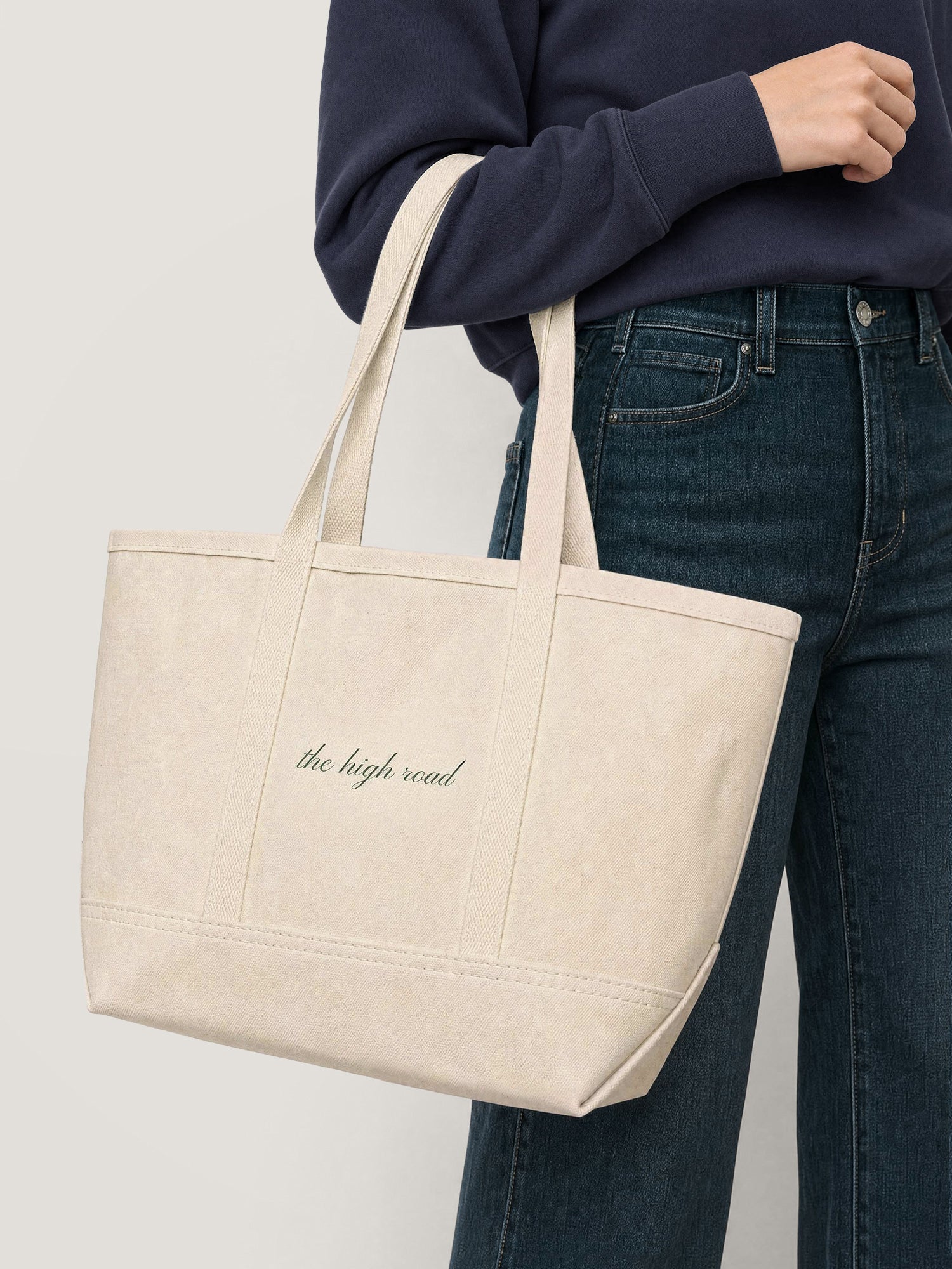 Model wearing the Veronica Beard x High Line "the high road" Sweatshirt and jeans, holding the Veronica Beard x High Line Tote. Closeup is on the tote.
