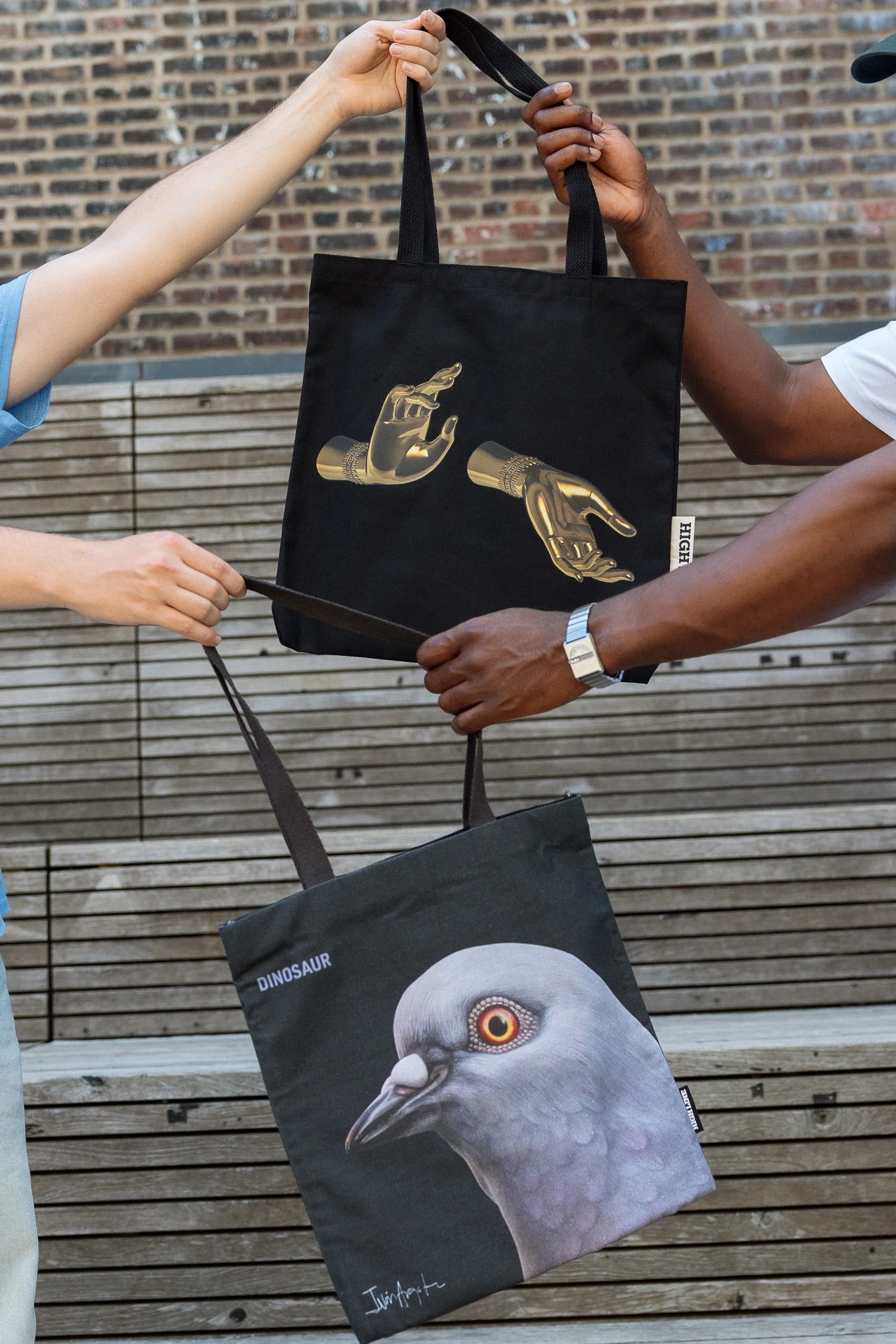 The Light That Shines Through the Universe Tote and Dinosaur Tote being passed between two people.