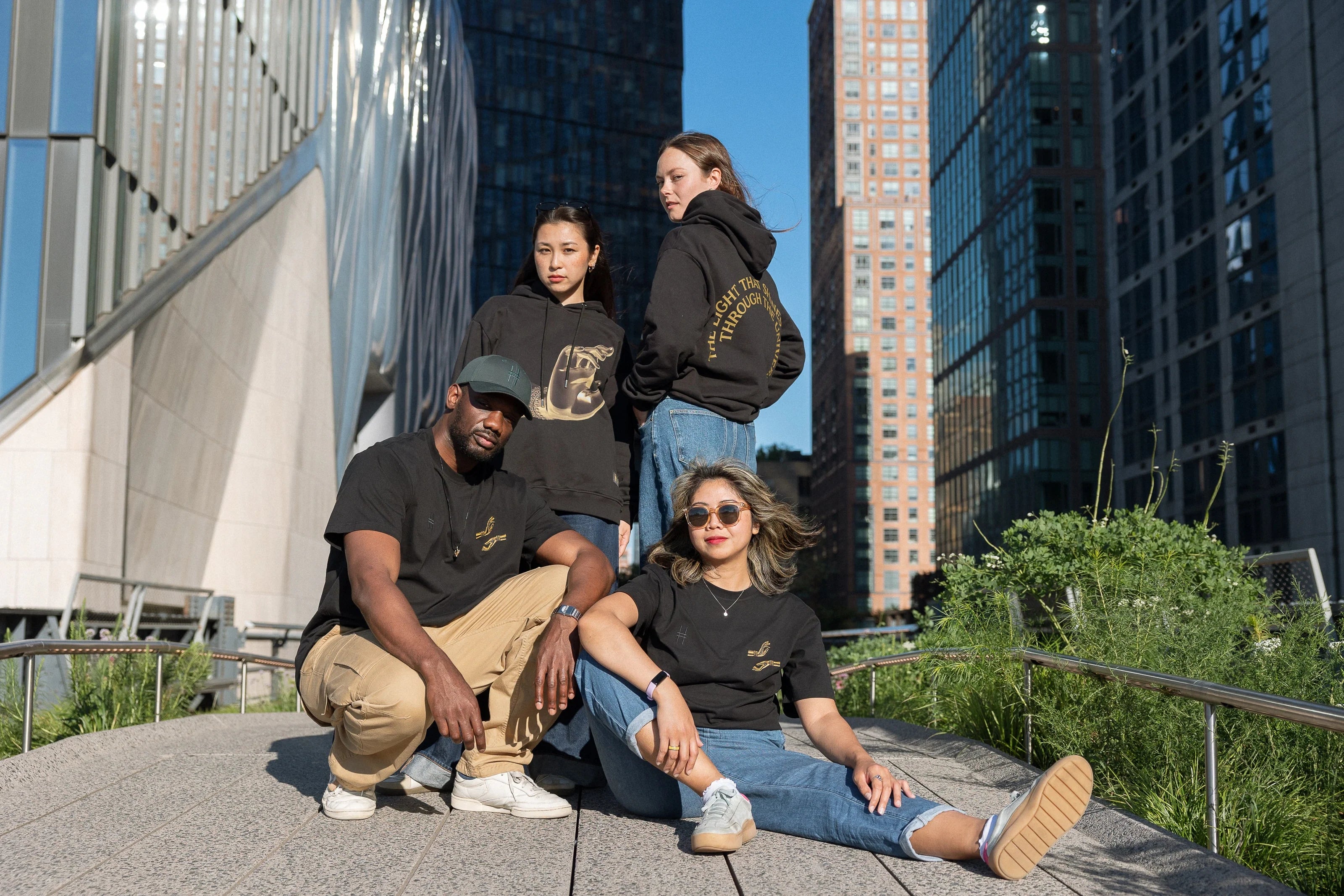 Four people, each wearing The Light That Shines... Hoodie or Tee on the northern end of the High Line.