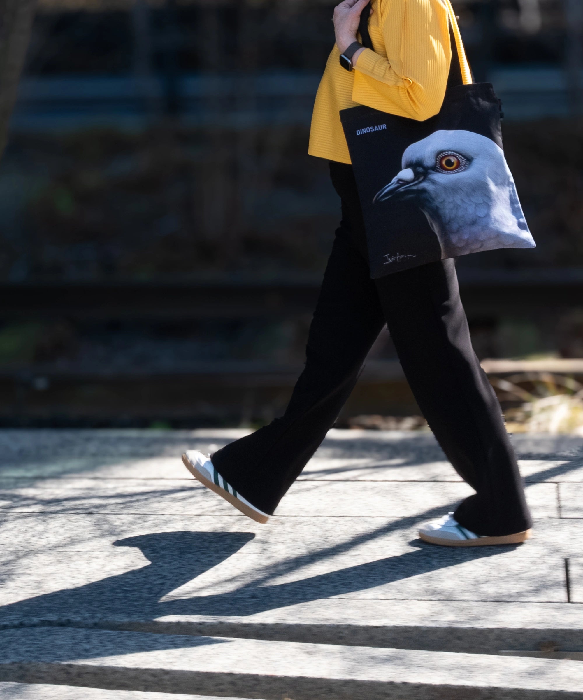 Woman walking along the High Line, holding the Dinosaur Tote.