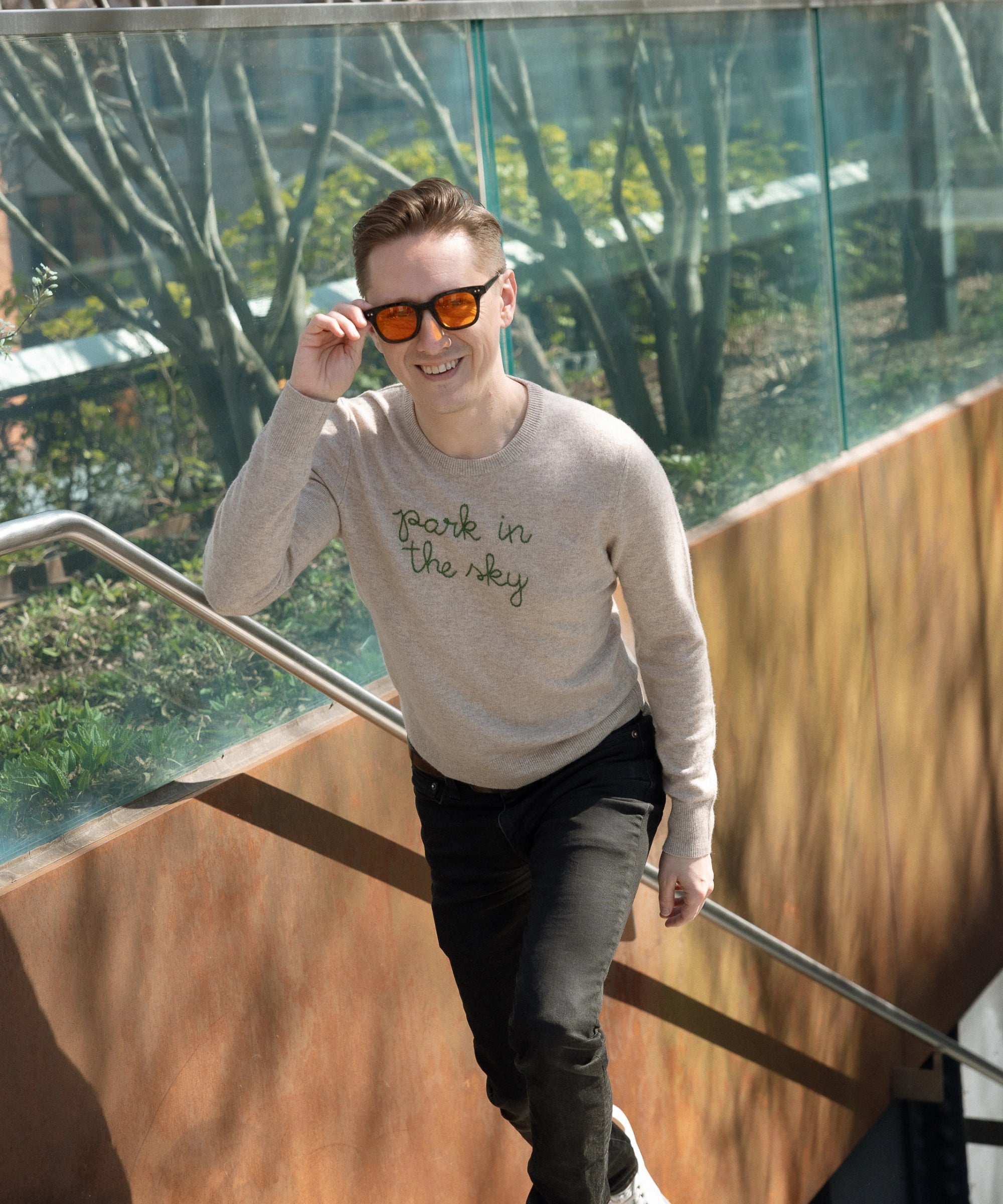 Man wearing the Lingua Franca x High Line Cashmere Sweater as he walks up the Gansevoort steps to the High Line.