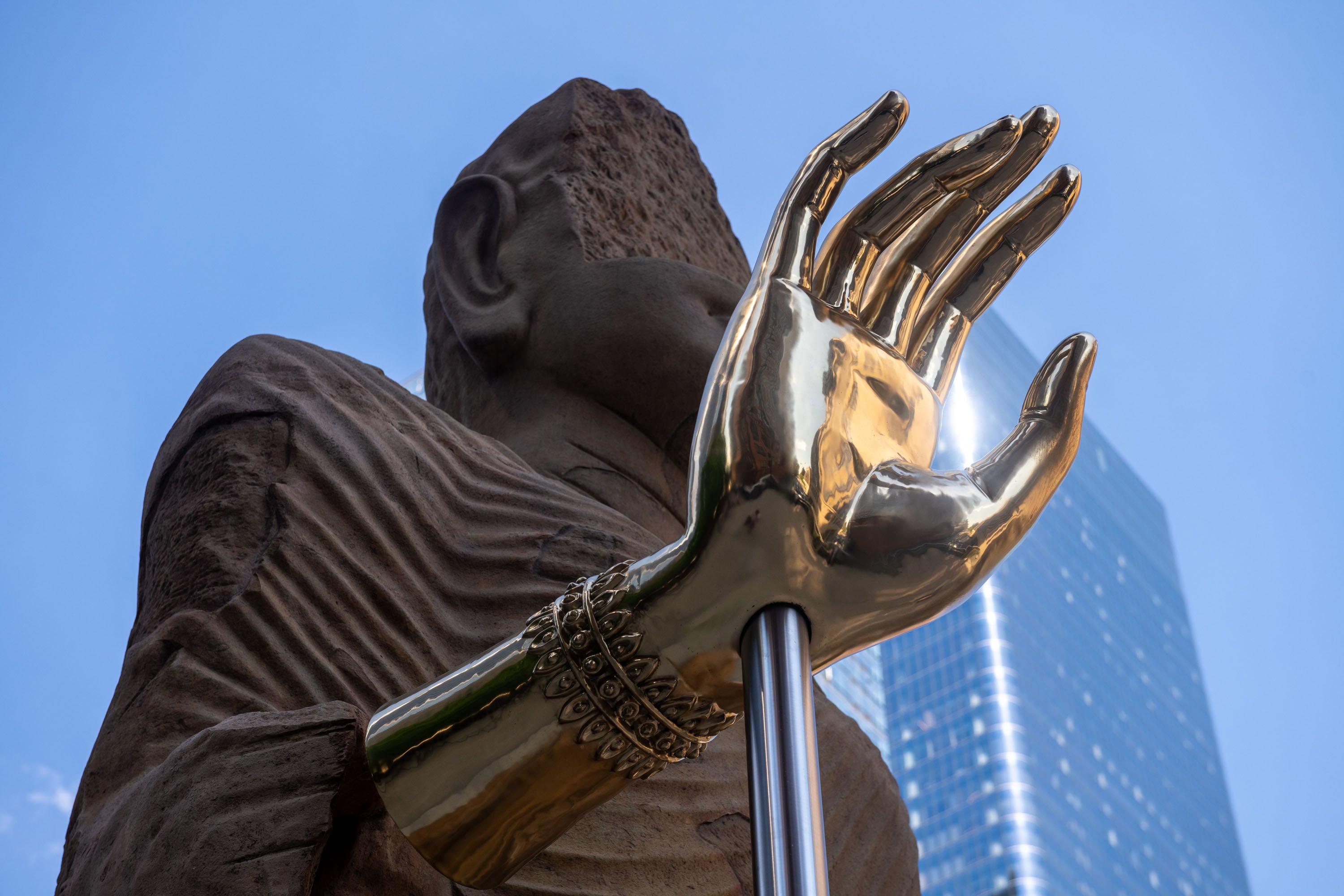 The Light That Shines Through the Universe, 2026, by Tuan Andrew Nguyen, shot looking up at the giant sandstone Buddha and right hand made from artillery brass. Photo by Timothy Schenck.