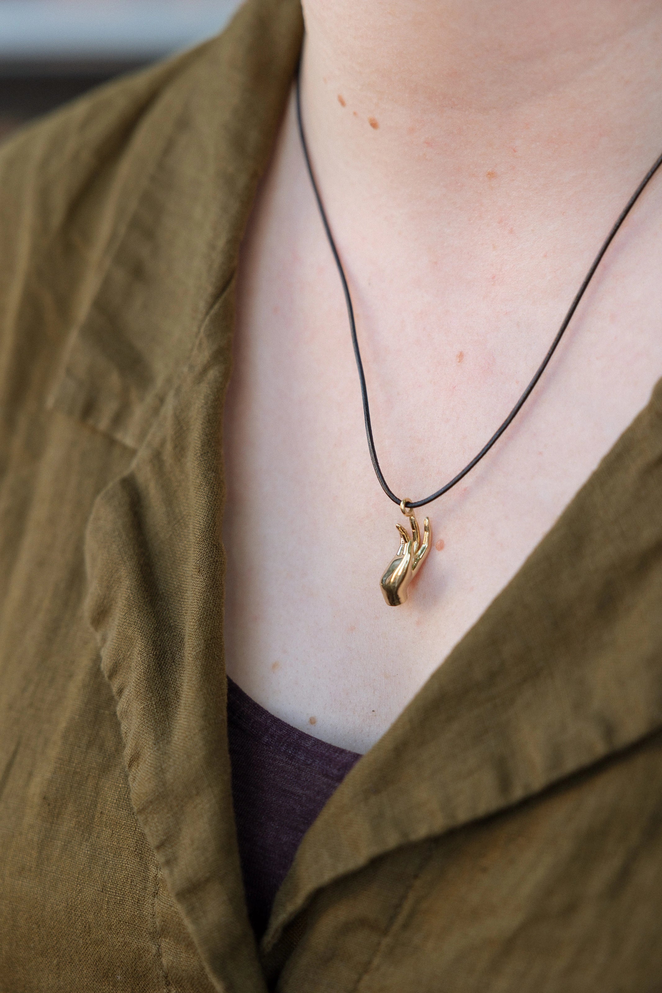 Abhaya mudra pendant on a person's neck.