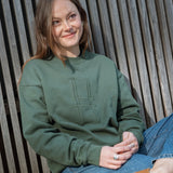 Woman wearing Big Icon Crewneck in Ivy with monochromatic embroidery details. Front features big High Line icon and High Line wordmark on sleeve. 
