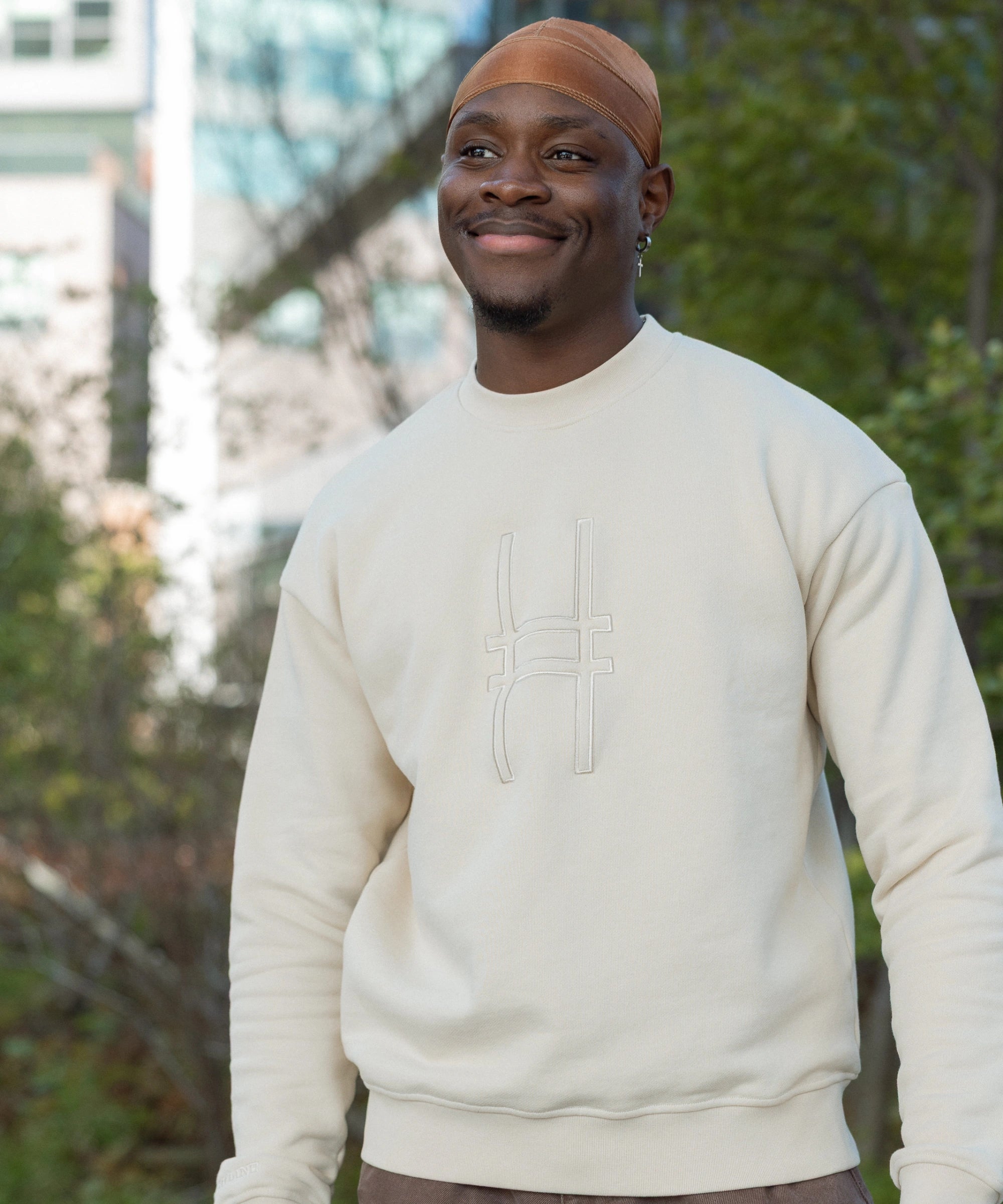Man wearing Big Icon Crewneck in River Birch with monochromatic High Line icon embroidered on the front standing on the High Line.