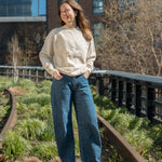 Woman standing on the High Line and wearing the Big Icon Crewneck in River Birch.