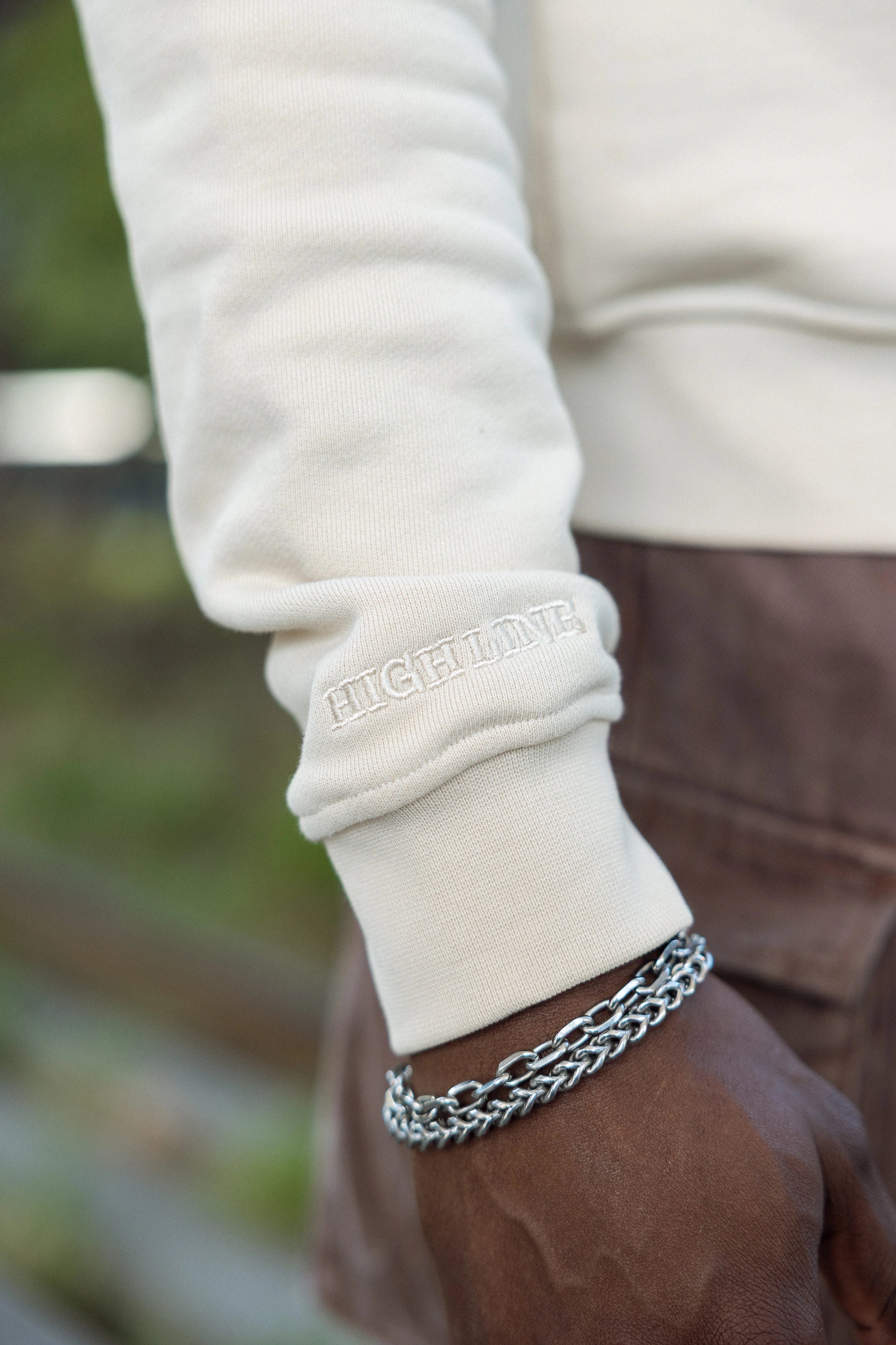 Closeup of the Big Icon Crewneck in River Birch with monochromatic High Line wordmark embroidered on the sleeve.