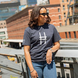 Woman wearing the High Line Icon Tee in navy and leaning against the railing of the High Line.