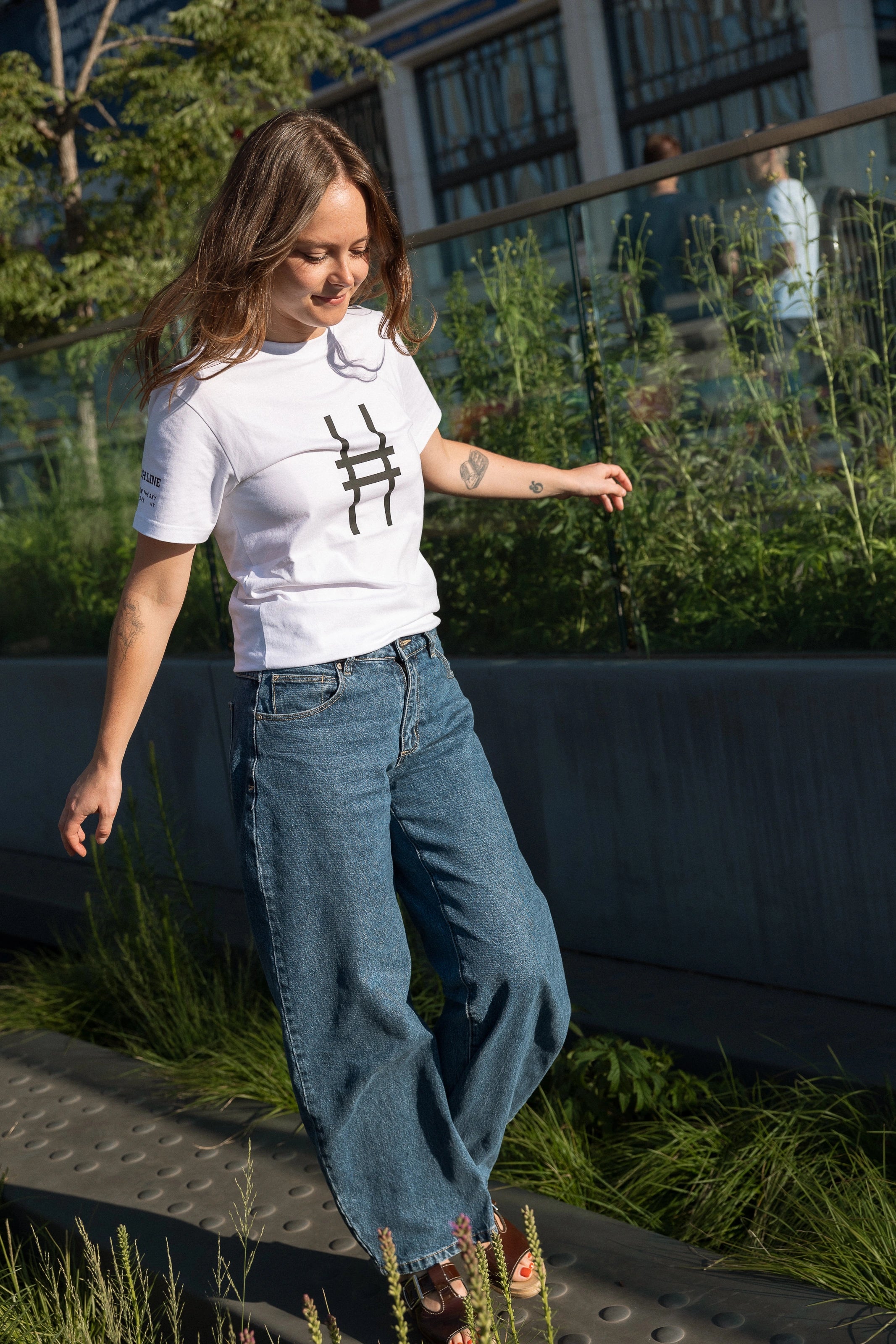 Woman walking on the Pershing Square Beams on the High Line and wearing the Big Icon Tee in white.