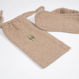 The Lingua Franca x High Line 100% Cashmere Eye Mask with travel case. This oatmeal-colored eye mask comes with a 100% cashmere travel bag embroidered with the High Line icon in green.