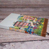 Community in the Sky Notebook featuring Jiaqi Wang's Nature in the City illustration and the High Line icon, shown laying against a bench.