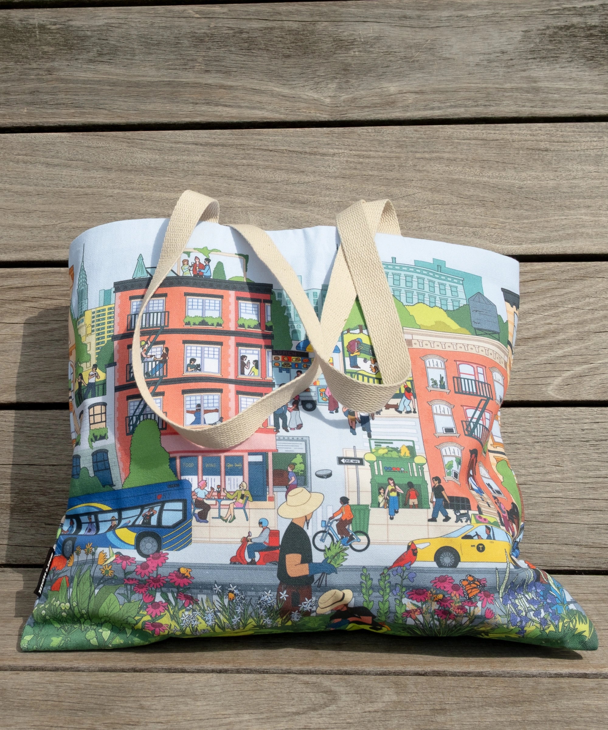 Community in the Sky Tote, featuring the Nature in the City mural illustrated by Jiaqi Wang, leaning on one of the sun deck loungers on the High Line.
