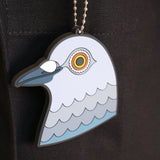 A close-up of the hanging pigeon head bag charm made from PVC against the Park in the Sky black cotton canvas tote.