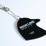 The backside of the Dinosaur-inspired pigeon head bag charm made from PVC. The back is all black with the High Line logo and "New York, New York" in white, as well as Pintrill, the manufacturer's logo.
