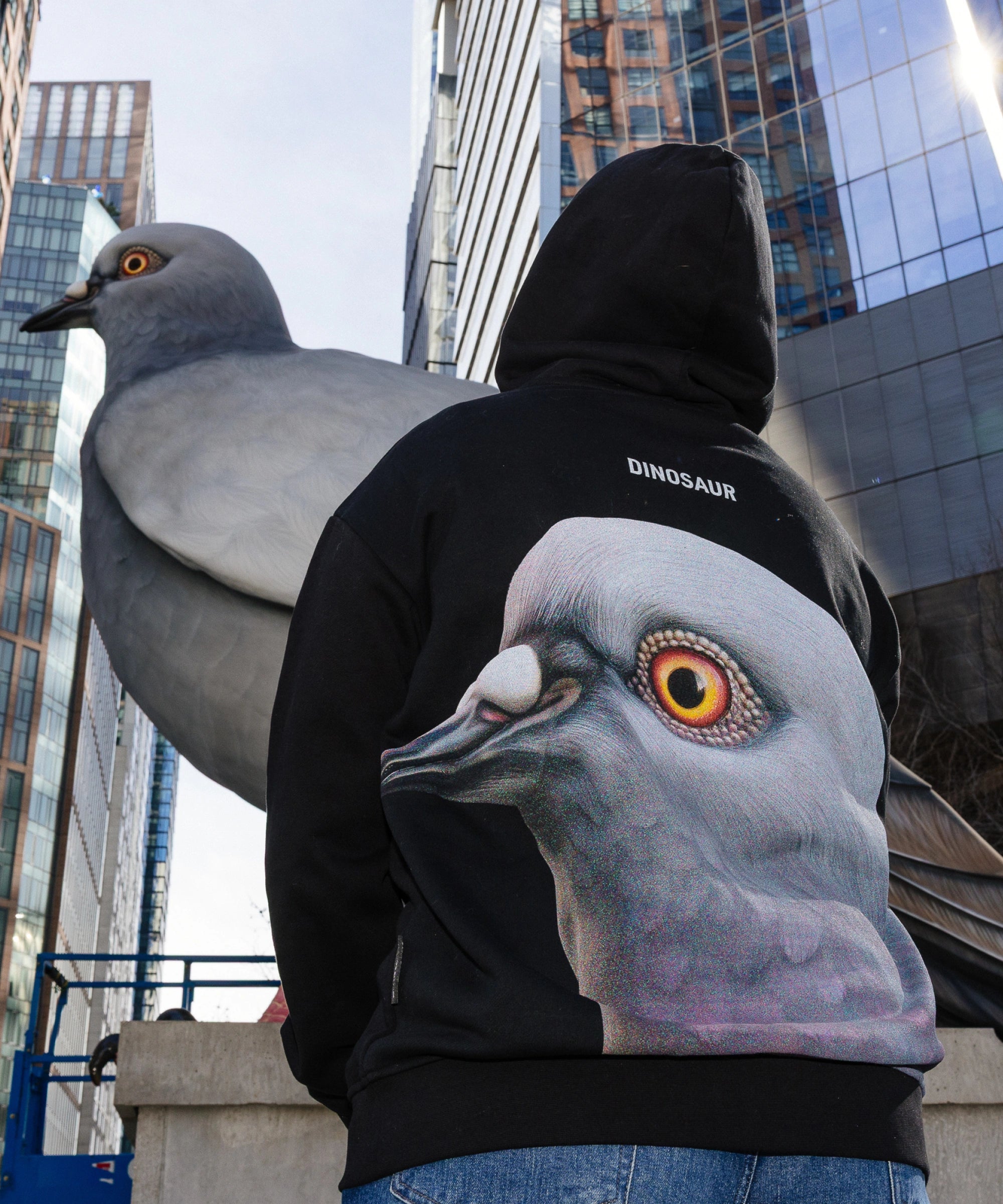 Person wearing the Dinosaur Hoodie, looking up at the Dinosaur statue when it was on view at the Plinth on the High Line. 