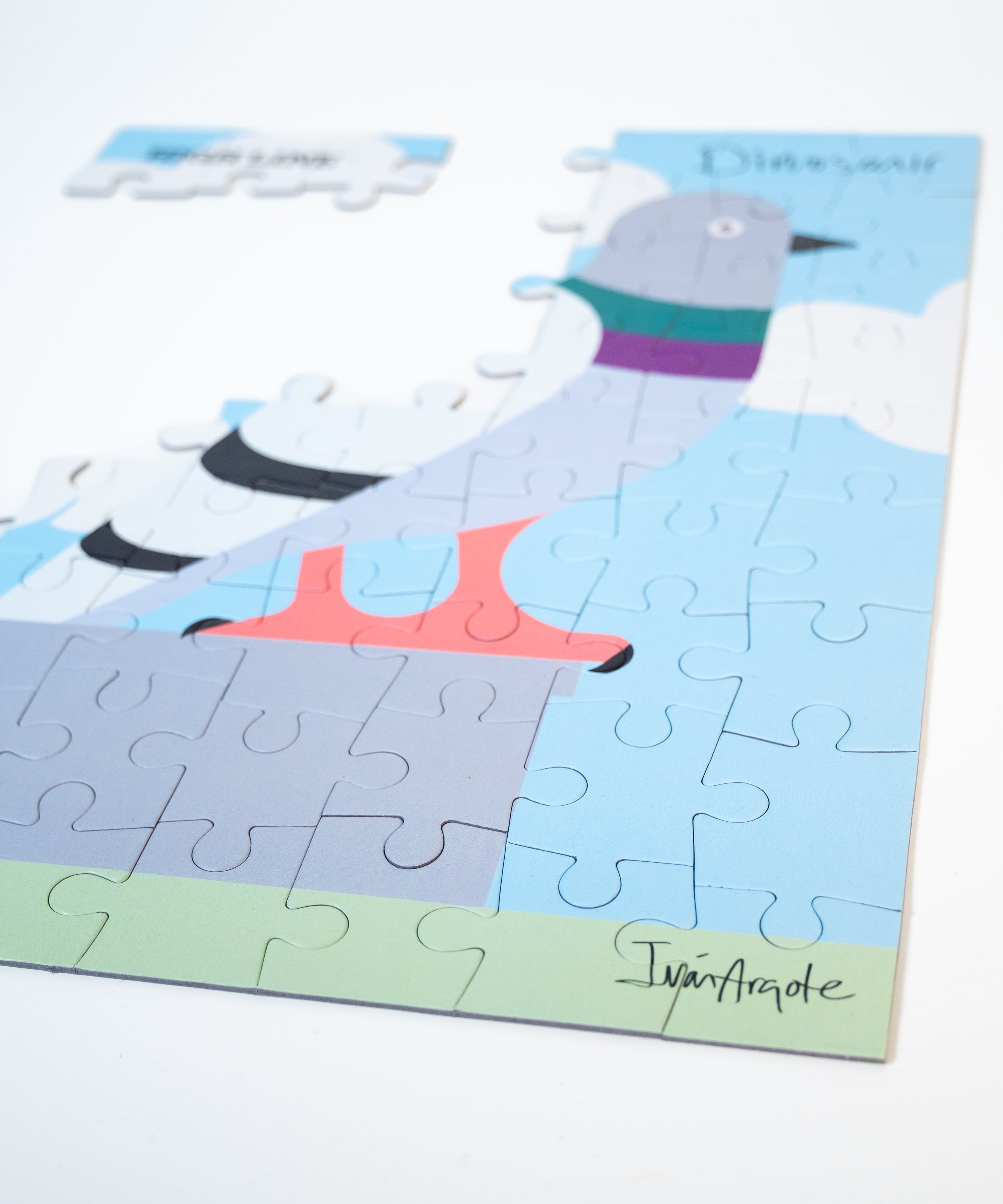 Partially completed Dinosaur Kids' Puzzle, showing the pigeon and the artist's signature in focus.