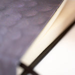 Close up of the notebook so you can see the pages and feather details.
