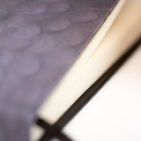 Close up of the notebook so you can see the pages and feather details.