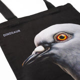 Closeup shot showing Dinosaur Tote front, with big pigeon head and "Dinosaur" screen-printed  on a black tote.