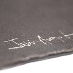 Closeup of Iván Argote's signature printed in white against the black tote.