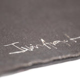 Closeup of Iván Argote's signature printed in white against the black tote.