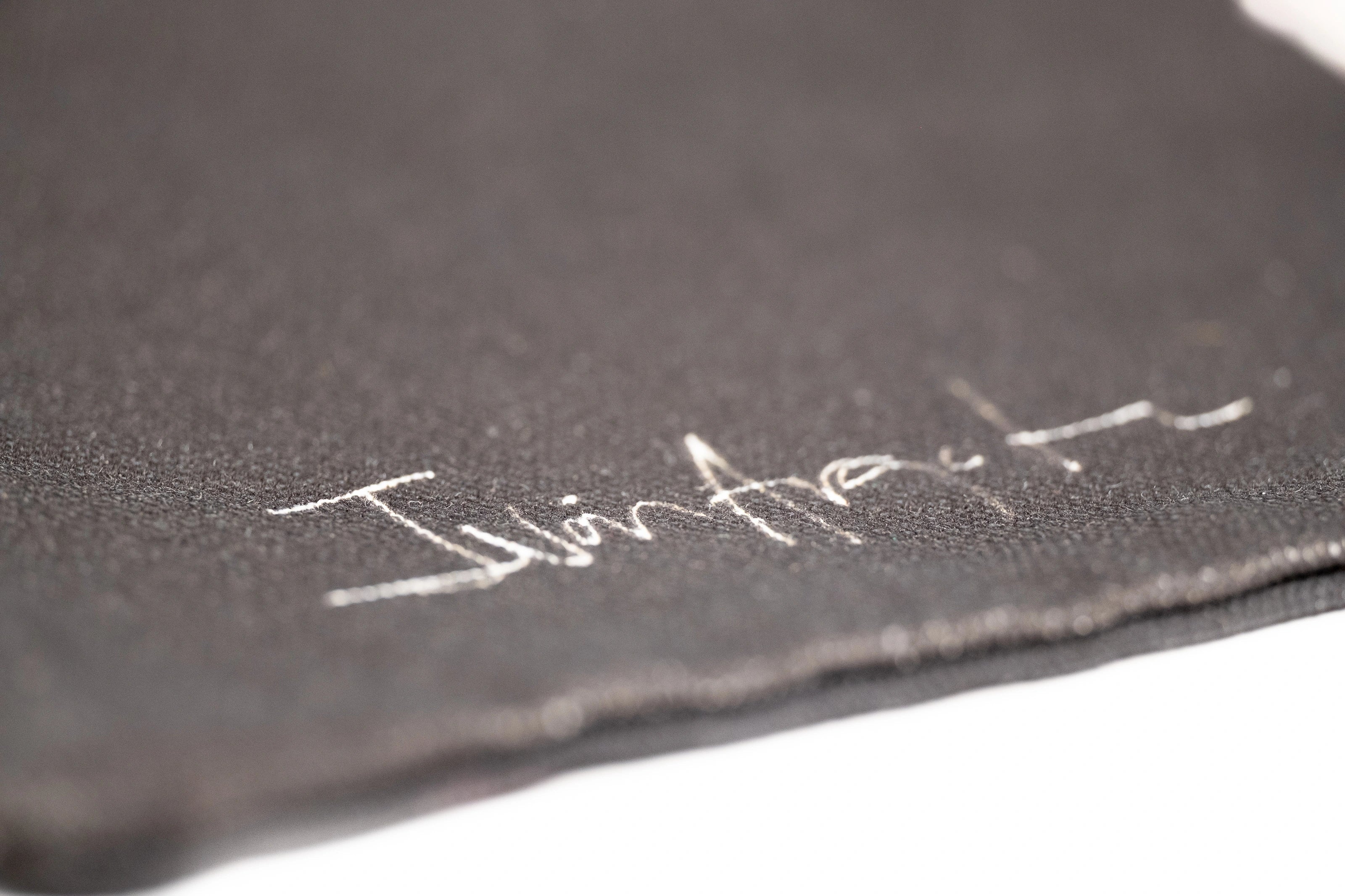 Closeup of Iván Argote's signature printed in white against the black tote.