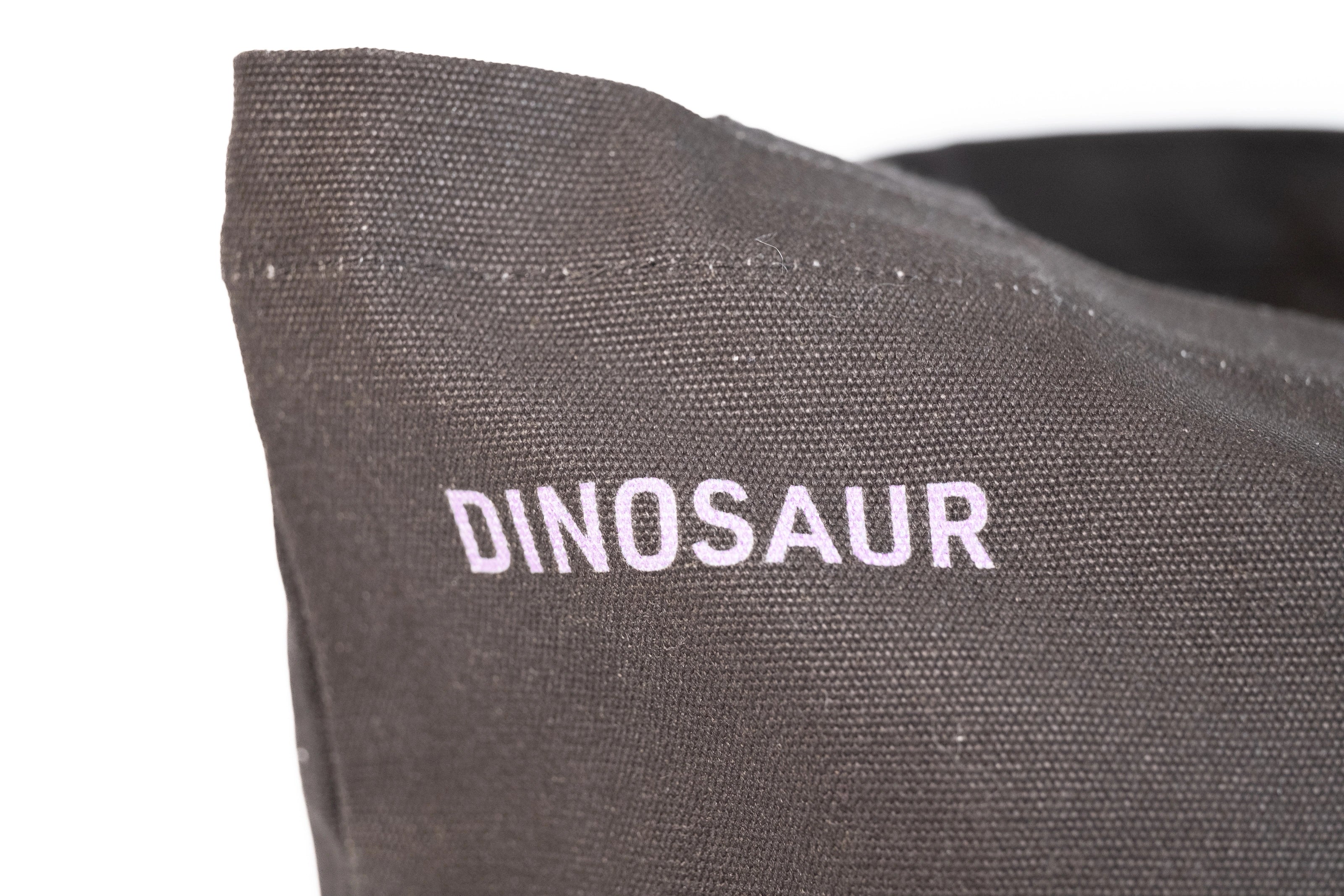 Closeup of "Dinosaur" printed in lavender against the black tote.