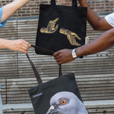 The Light That Shines Through the Universe Tote and Dinosaur Tote being passed between two people.