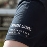 Sleeve detail. High Line wordmark and park in the sky tagline in white against the navy tee.