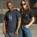 Two people, one wearing the Big Icon Tee in navy, and the other wearing the High Line Embroidered Pocket Tee.