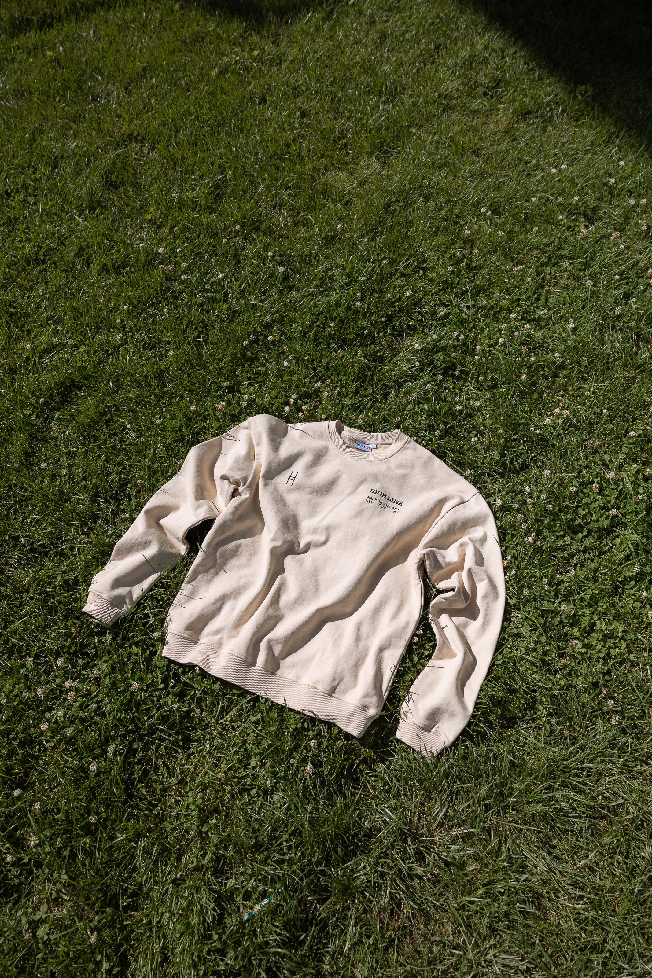 High Line Crewneck lying on the lawn on the High Line at 23rd street.