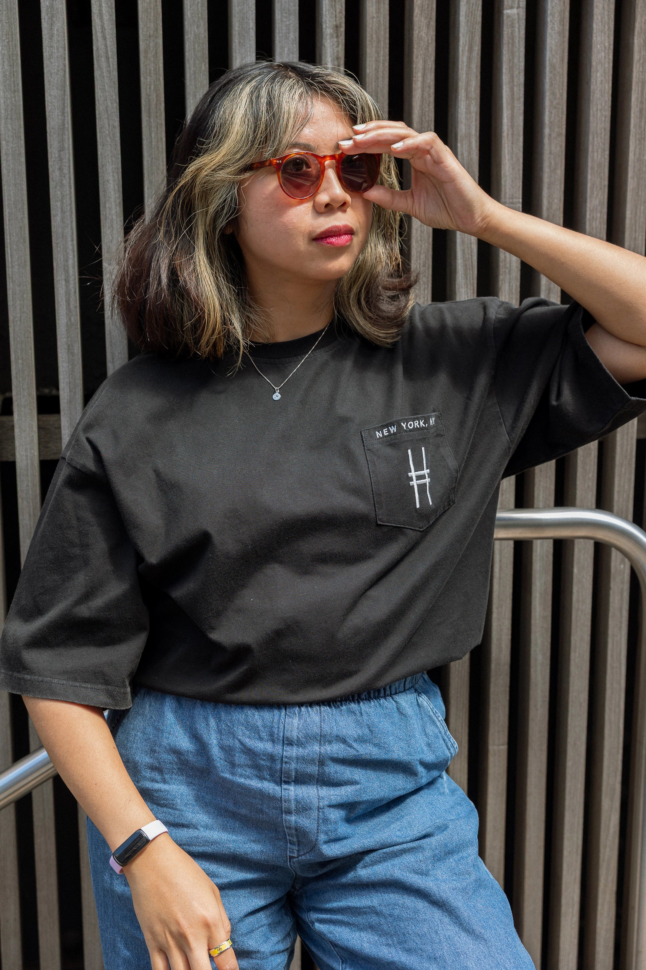 Woman wearing High Line Icon Embroidered Pocket Tee and adjusting her sunglasses.