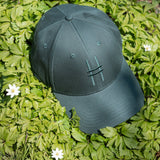High Line Icon Cap in a bed of greenery dotted with flowers.