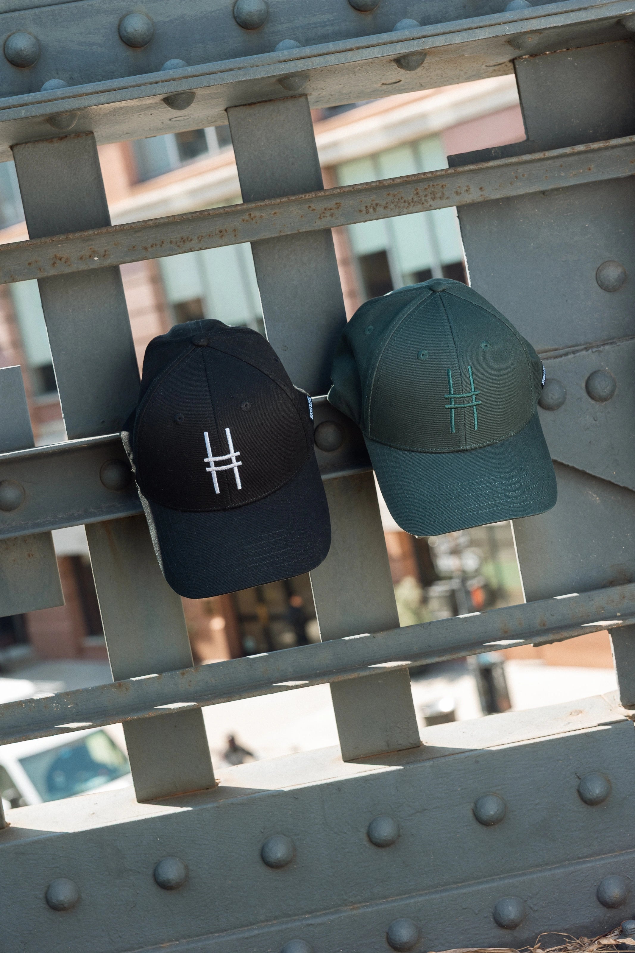 Both High Line Icon Caps hanging off of the historic High Line railing.