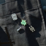 All the High Line Icon collection pins on the Park in the Sky Tote against the High Line railing.