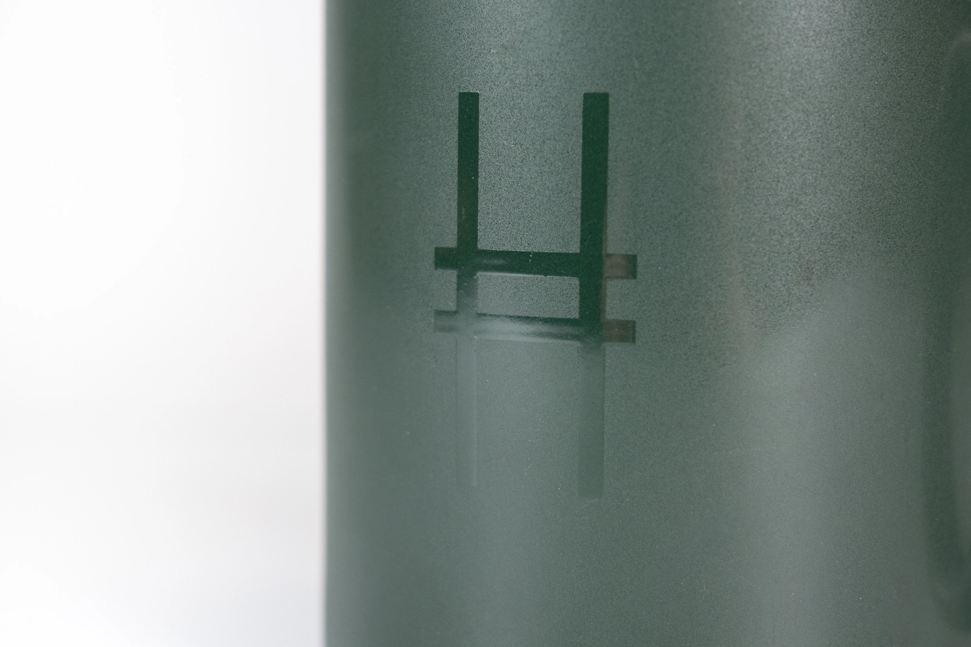 Closeup of High Line Mug in Ivy, featuring the High Line icon in gloss against dark green matte ceramic.