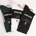 Three pairs of crew socks in Ivy, white, and black, each with a High Line belly-band.