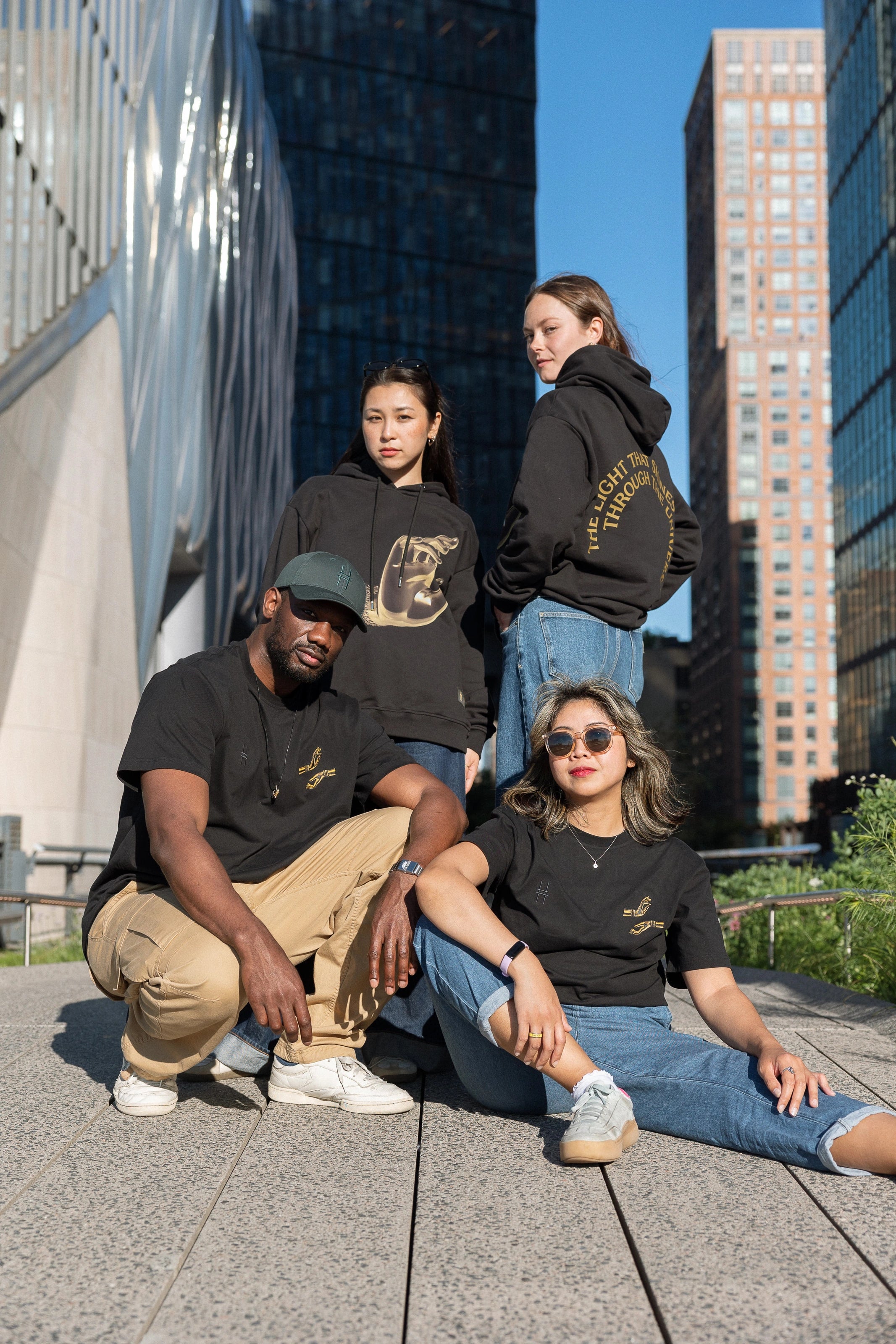Four people, each wearing The Light That Shines... Hoodie or Tee, on the northern end of the High Line.