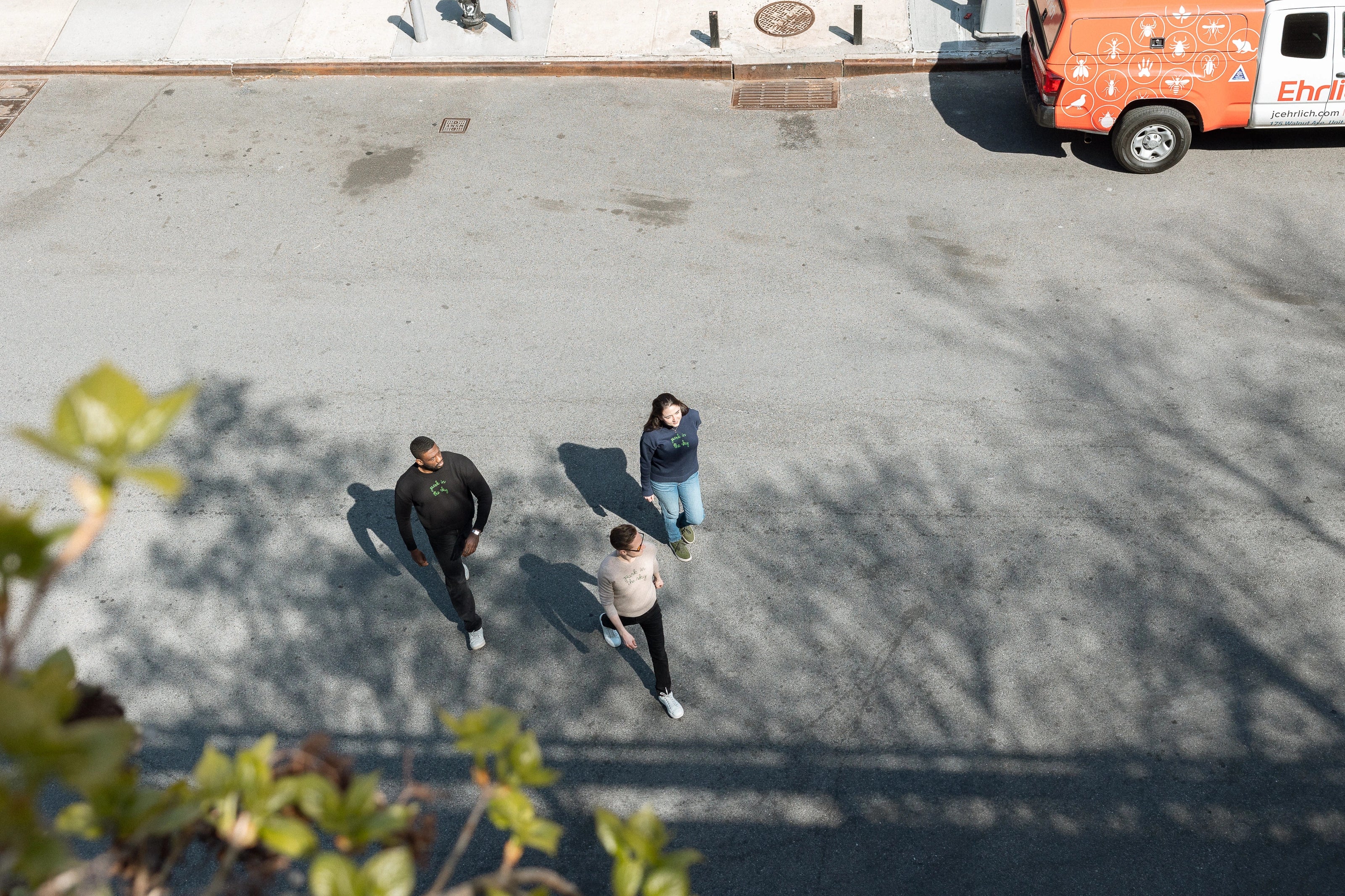 Three people, each in a Lingua Franca x High Line sweater, crossing the street to the High Line.