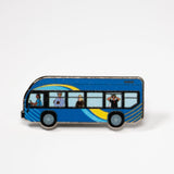 The MTA Bus enamel pin—MTA Bus with driver and passengers, including the sightseer, illustrated by Jiaqi Wang.