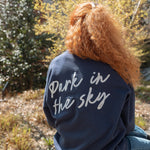 Woman wearing Park in the Sky Crewneck while sitting on the High Line.