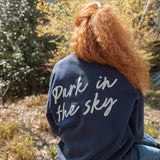 Woman wearing Park in the Sky Crewneck while sitting on the High Line.