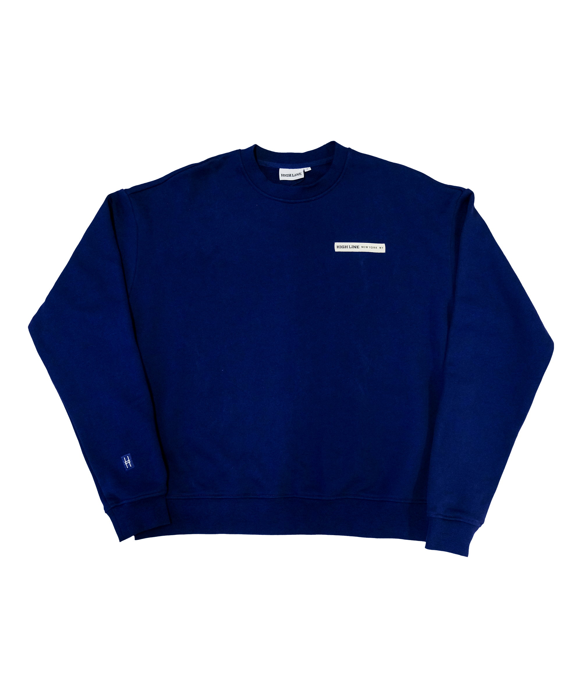 Park in the Sky Crewneck in navy. Front features a chest ribbon detail with the High Line logo and "New York" as well as a small woven patch with the High Line railroad track-inspired "H" icon sewn on the right sleeve. The navy is a deep, saturated blue.