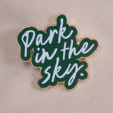 Our Park in the Sky pin against a cream sweatshirt.