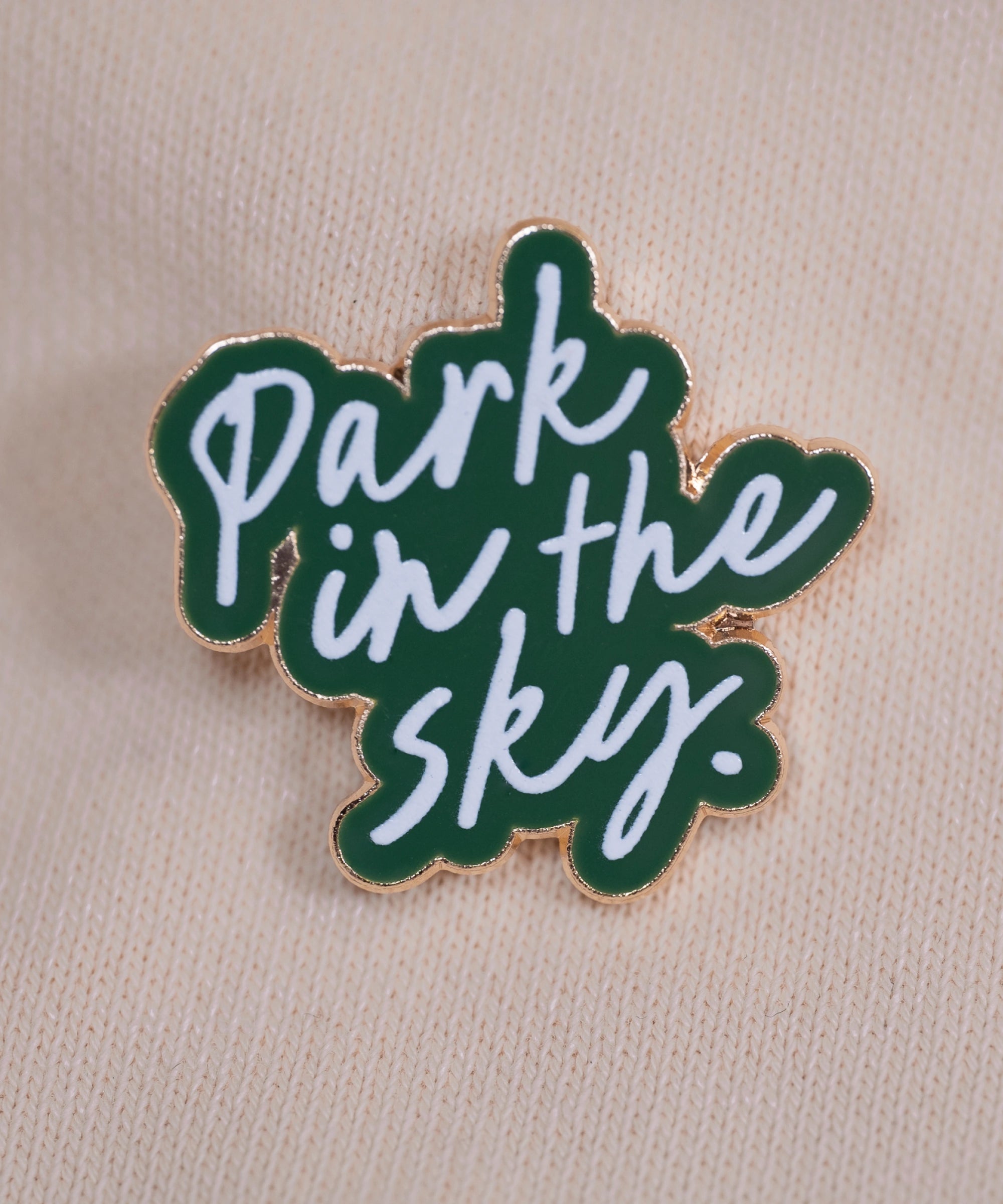 Our Park in the Sky pin against a cream sweatshirt.
