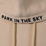 Park in the Sky embroidered hoodie in River Birch. Closeup of "PARK IN THE SKY" embroidered on the hood along the seam.