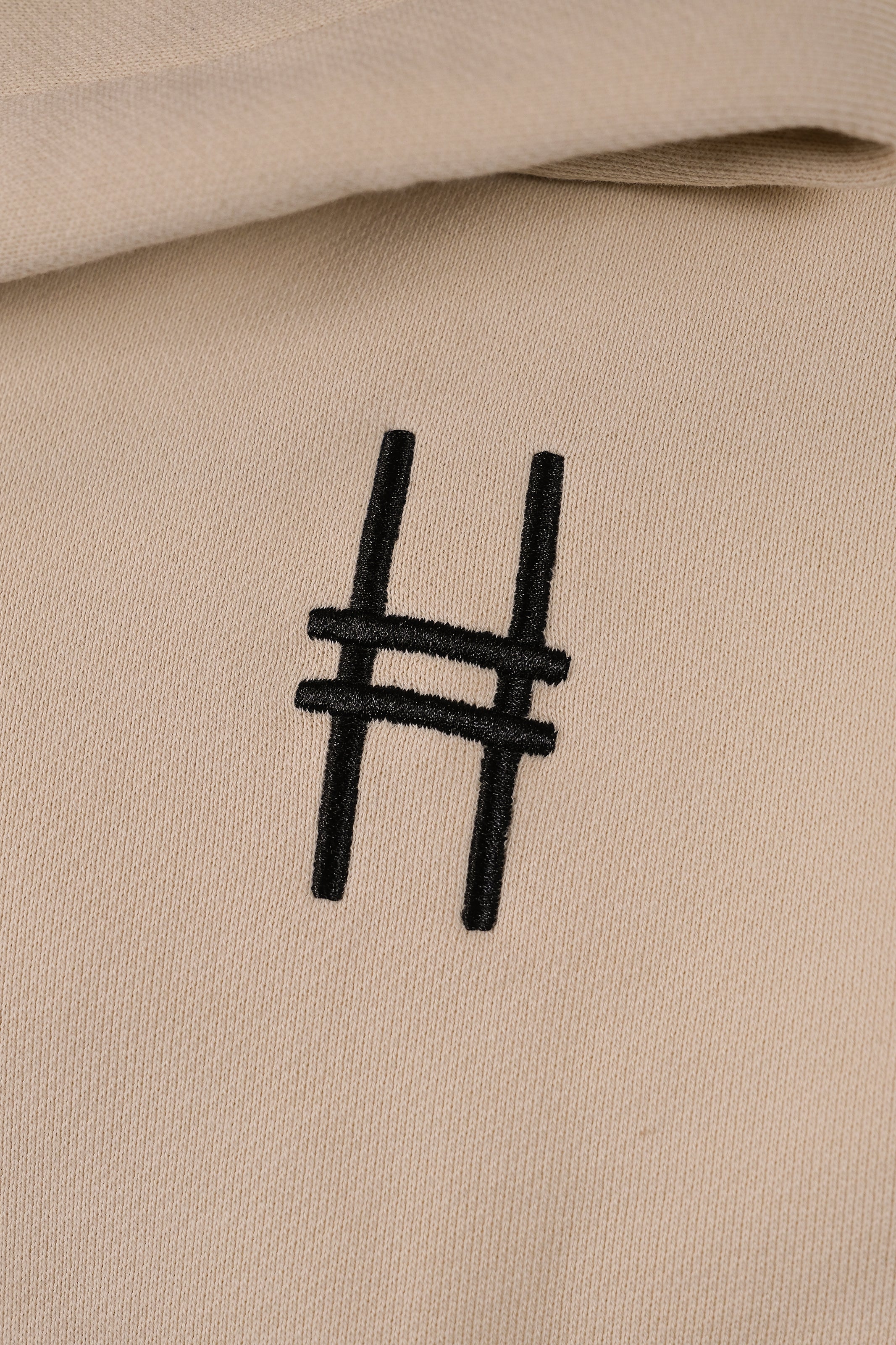Front chest embroidery detail with High Line icon in black against the River Birch fabric.