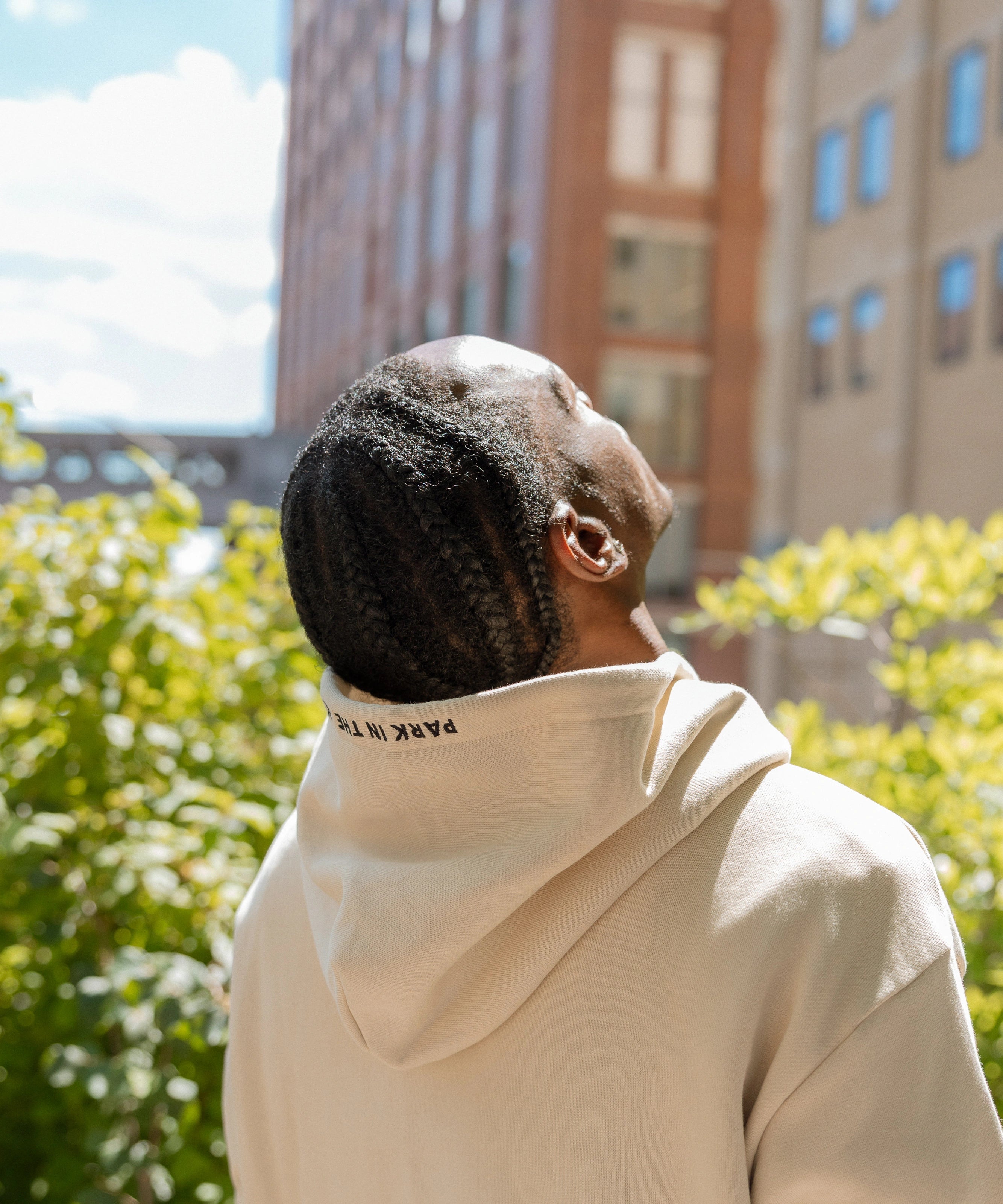 Man wearing the Park in the Sky Hoodie with hood embroidery detail visible, looking up and feeling the sun on his face.