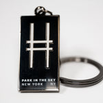 Black rectangular enamel keychain with the High Line railroad-track "H" icon and "Park in the Sky, New York NY" on a white background.