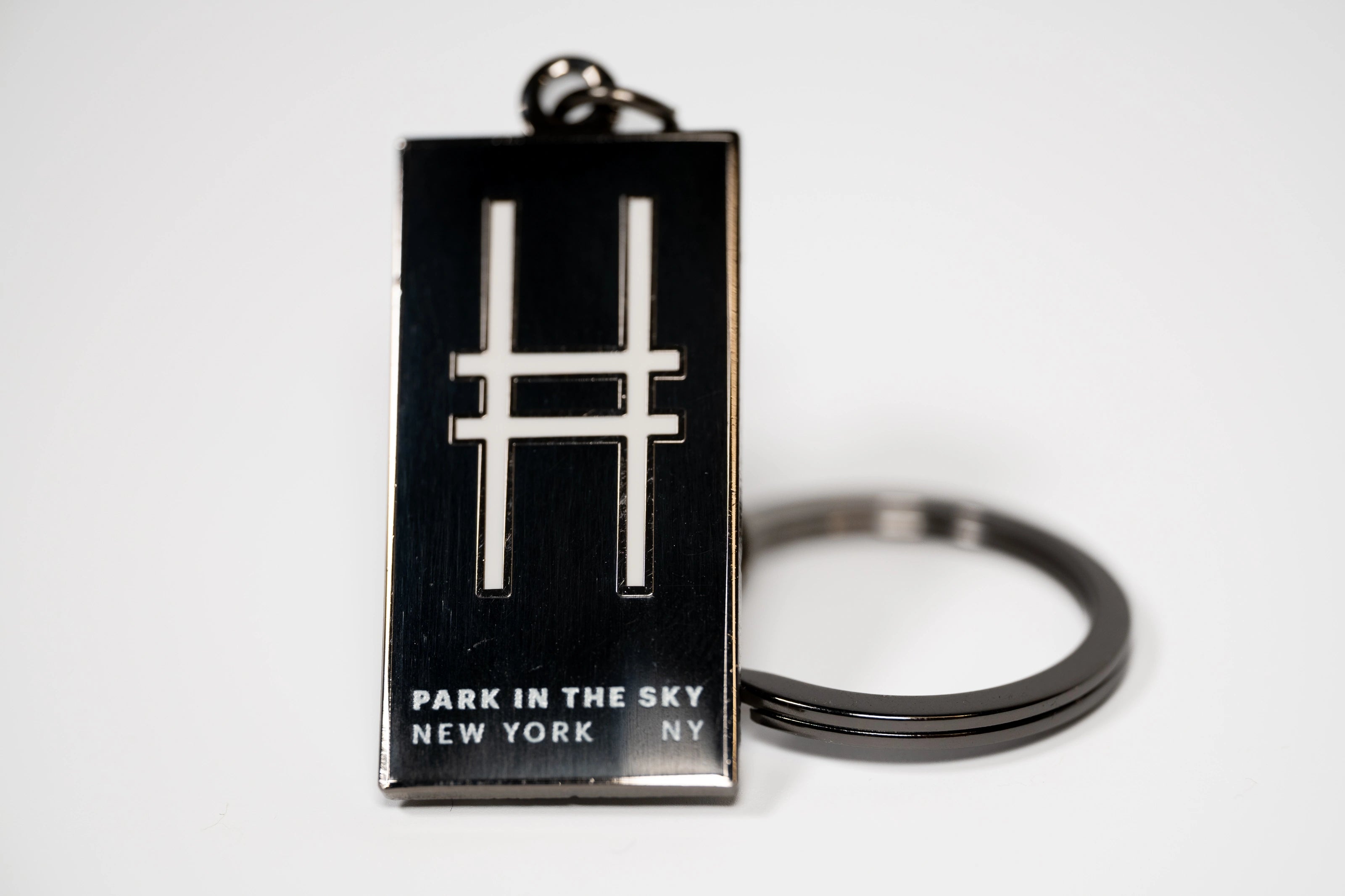 Black rectangular enamel keychain with the High Line railroad-track "H" icon and "Park in the Sky, New York NY" on a white background.